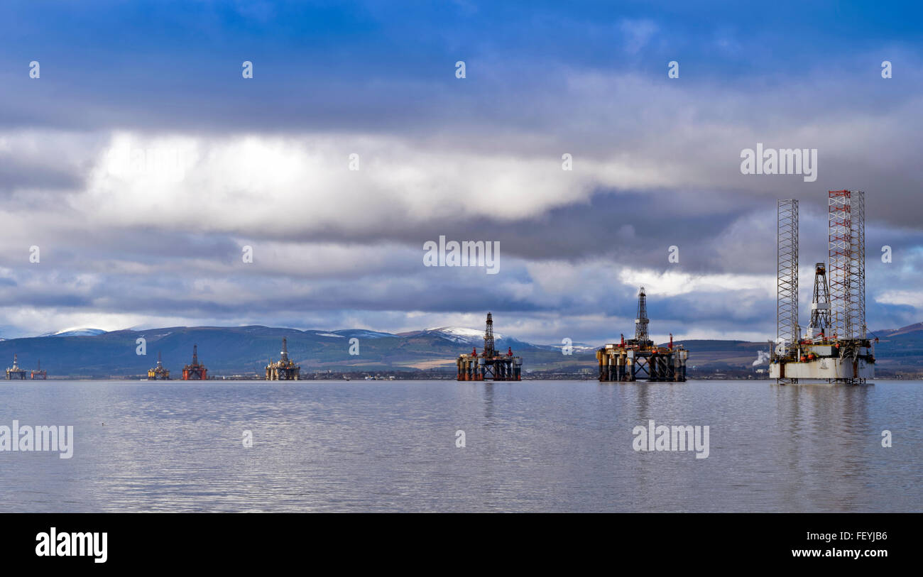 EIGHT NORTH SEA OIL RIGS UNDER REPAIR IN THE CROMARTY FIRTH WITH SNOW CAPPED HILLS AND INVERGORDON IN THE DISTANCE Stock Photo