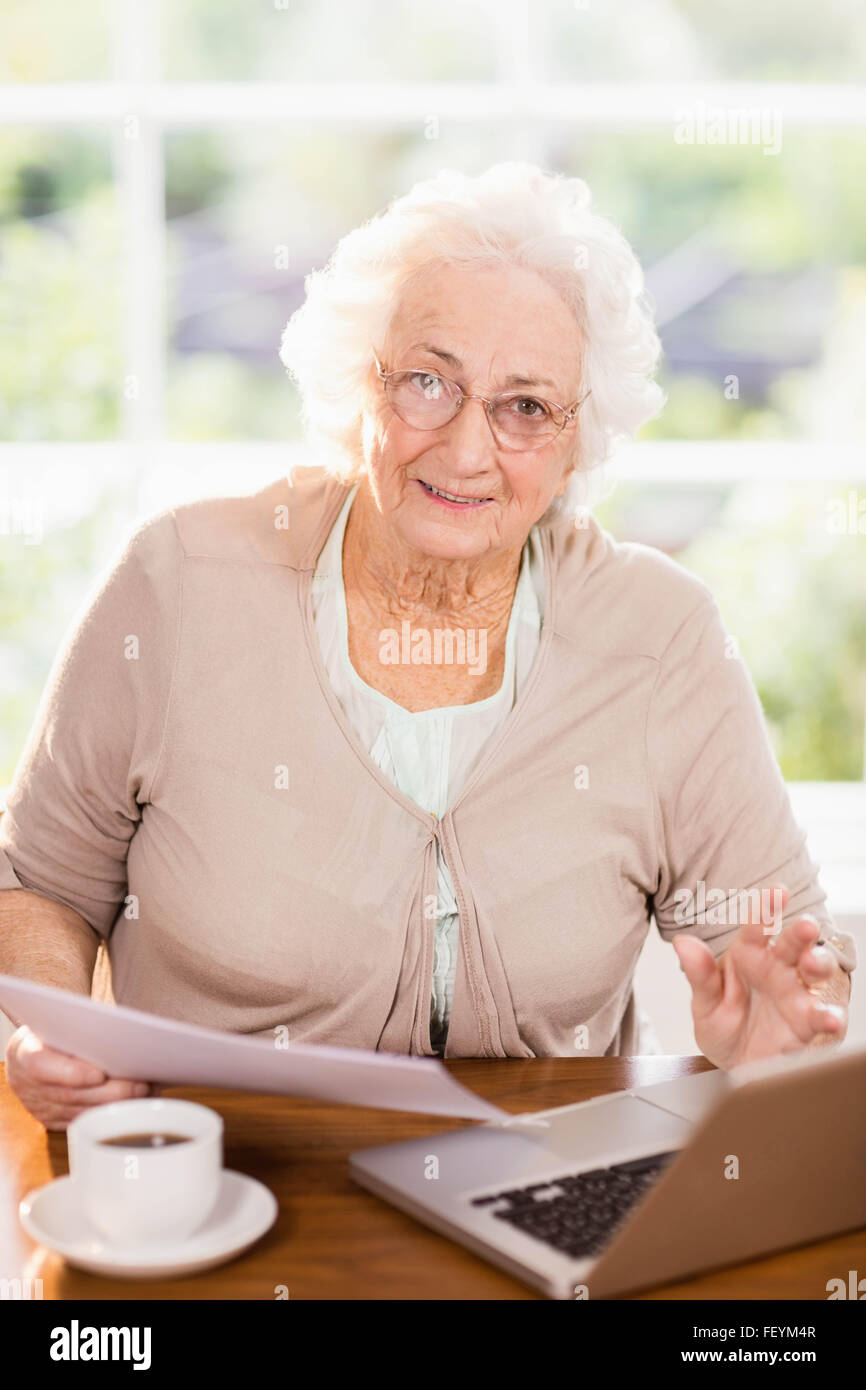 Senior woman dealing with documents while using laptop Stock Photo