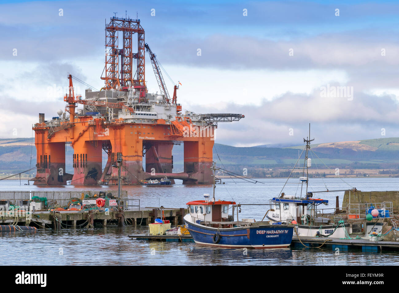 NORTH SEA OIL RIG WEST PHOENIX TOWERS OVER BOATS MOORED IN CROMARTY HARBOUR CROMARTY FIRTH SCOTLAND Stock Photo