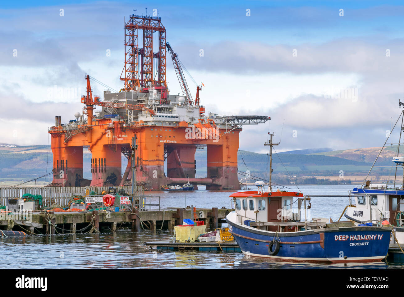 NORTH SEA OIL RIG WEST PHOENIX TOWERS OVER FISHING BOATS MOORED IN CROMARTY HARBOUR CROMARTY FIRTH SCOTLAND Stock Photo