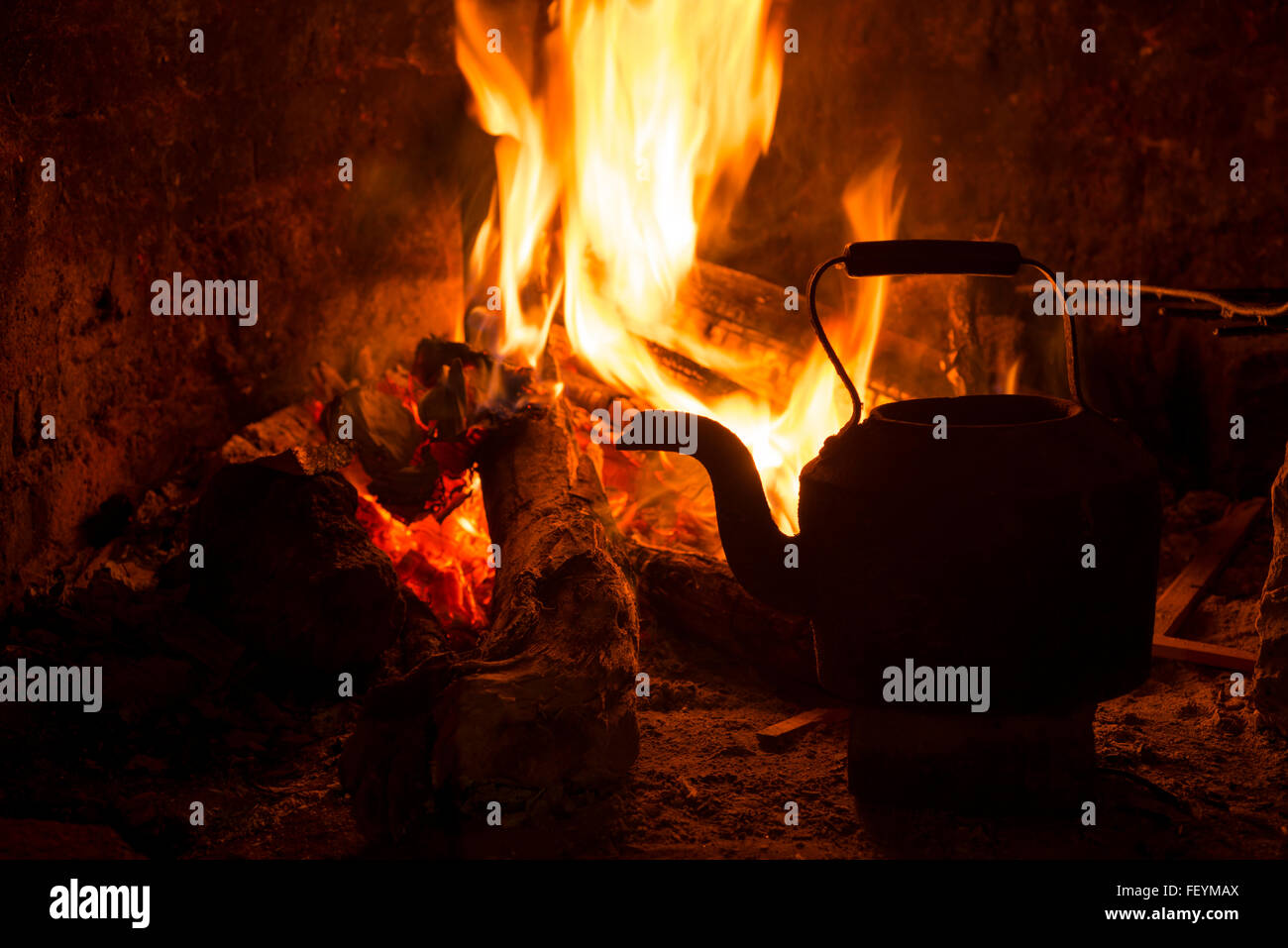 Kettle in fireplace, fire and wood burning. Cozy winter holiday cabin