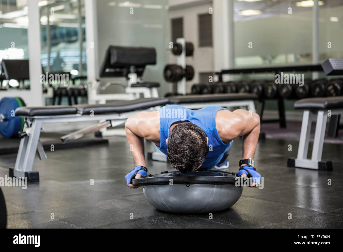 Muscular man doing push up with bosu ball Stock Photo