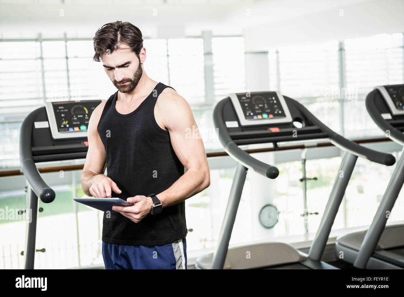 Serious man using tablet against treadmills Stock Photo - Alamy