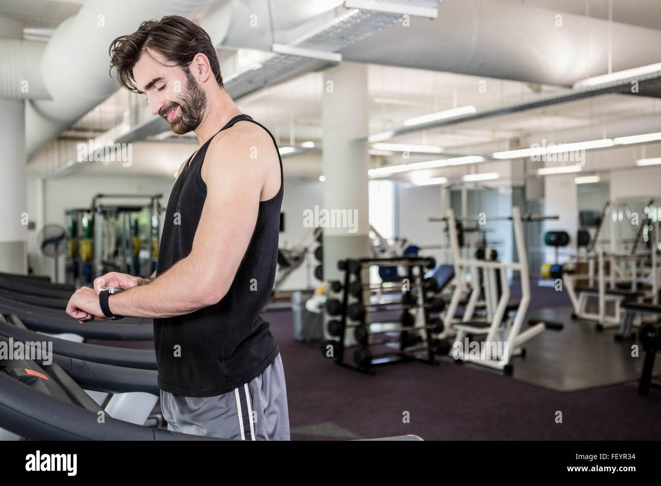 Smiling man on treadmill looking at smartwatch Stock Photo - Alamy