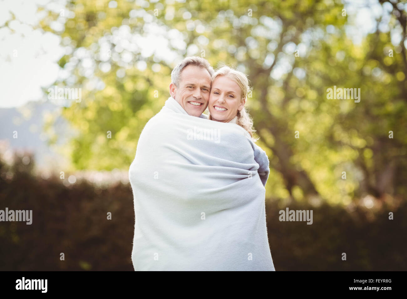 Cute couple hugging with a blanket around Stock Photo - Alamy