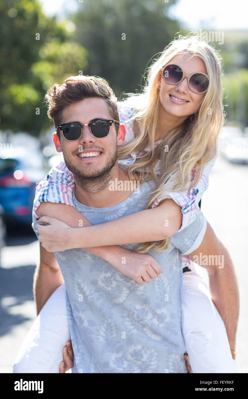 Hip man giving piggy back to his girlfriend Stock Photo