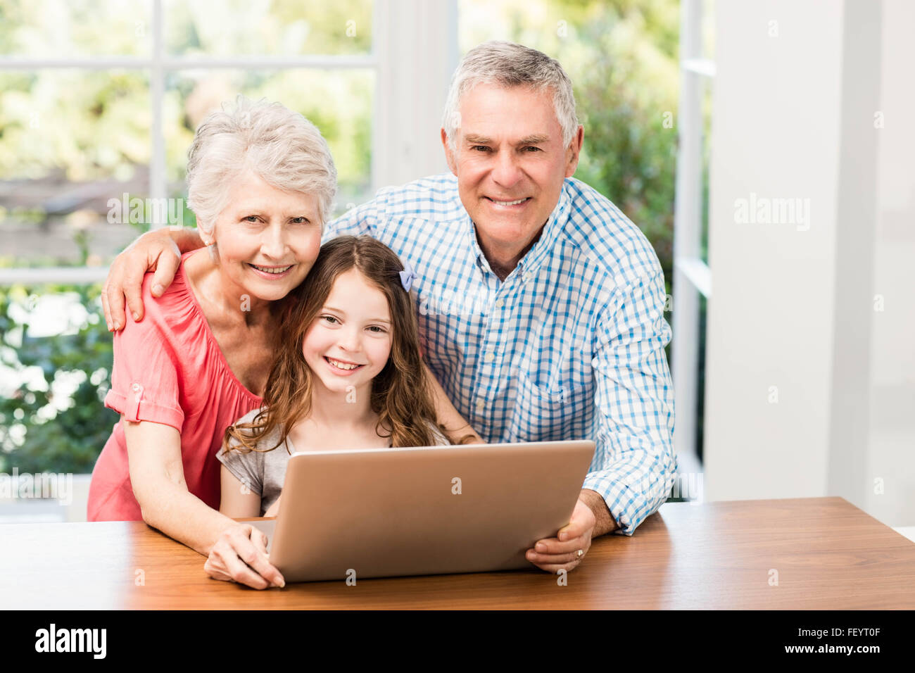 Portrait of smiling grandparents and granddaughter using laptop Stock Photo