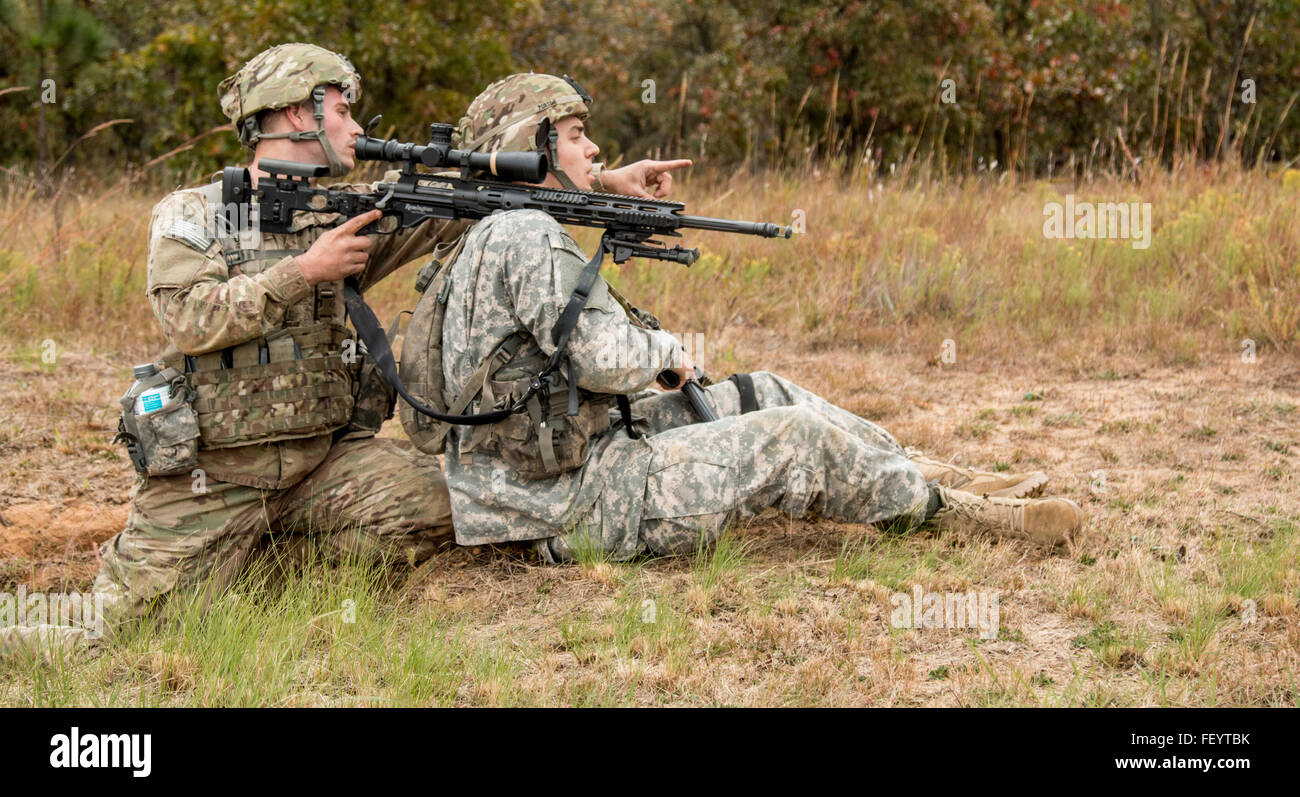 A sniper with the 1st Squadron, 73rd Calvary Regiment, 2nd Brigade Combat Team, 82nd Airborne Division, part of the Global Response Force, uses his partner for stabilization and assesses a would-be target in preparation for the upcoming Combined Joint Operational Access Exercise 16-01, Oct. 26, 2015, on Fort Bragg, N.C. The squadron will conduct several rehearsals this week, during the day and at night, in preparation for a joint forcible entry operation during CJOAX 16-01, where they will jump with live ammunition and move to the objective to conduct a live fire exercise. Stock Photo