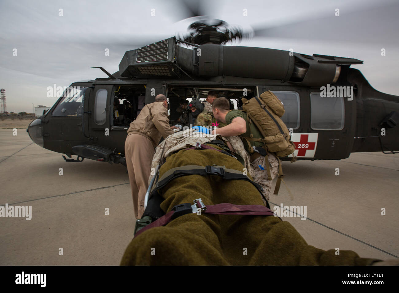 U.S. Navy Corpsmen with Special Purpose Marine Air-Ground Task Force-Crisis Response-Central Command (SPMAGTF-CR-CC) transport Cpl. Galton Hua, a simulated casualty, with Charlie Co., 1st Battalion, 7th Marine Regiment, SPMAGTF-CR-CC, to a U.S. Army UH-60 Blackhawk aircraft for air evacuation during a mass casualty exercise at an undisclosed location in Southwest Asia, Dec. 23, 2015. The training familiarized U.S. joint services and partner nations with various techniques and procedures while simultaneously handling multiple casualties. Stock Photo