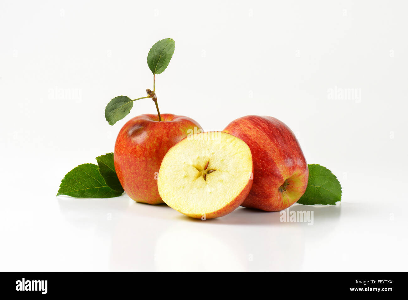 two and half apples with leaves on white background Stock Photo