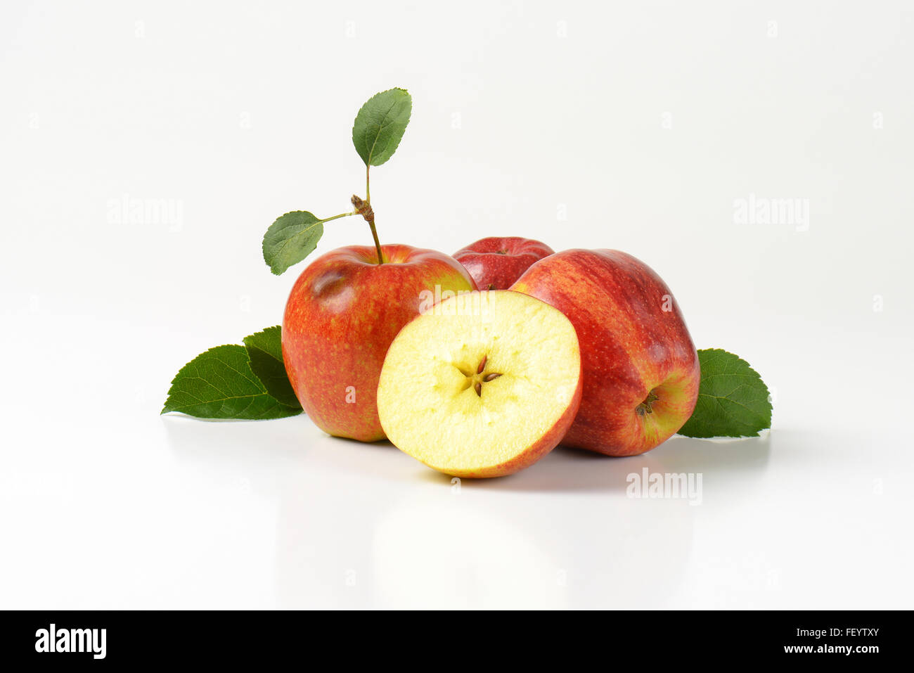 three and half apples with leaves on white background Stock Photo