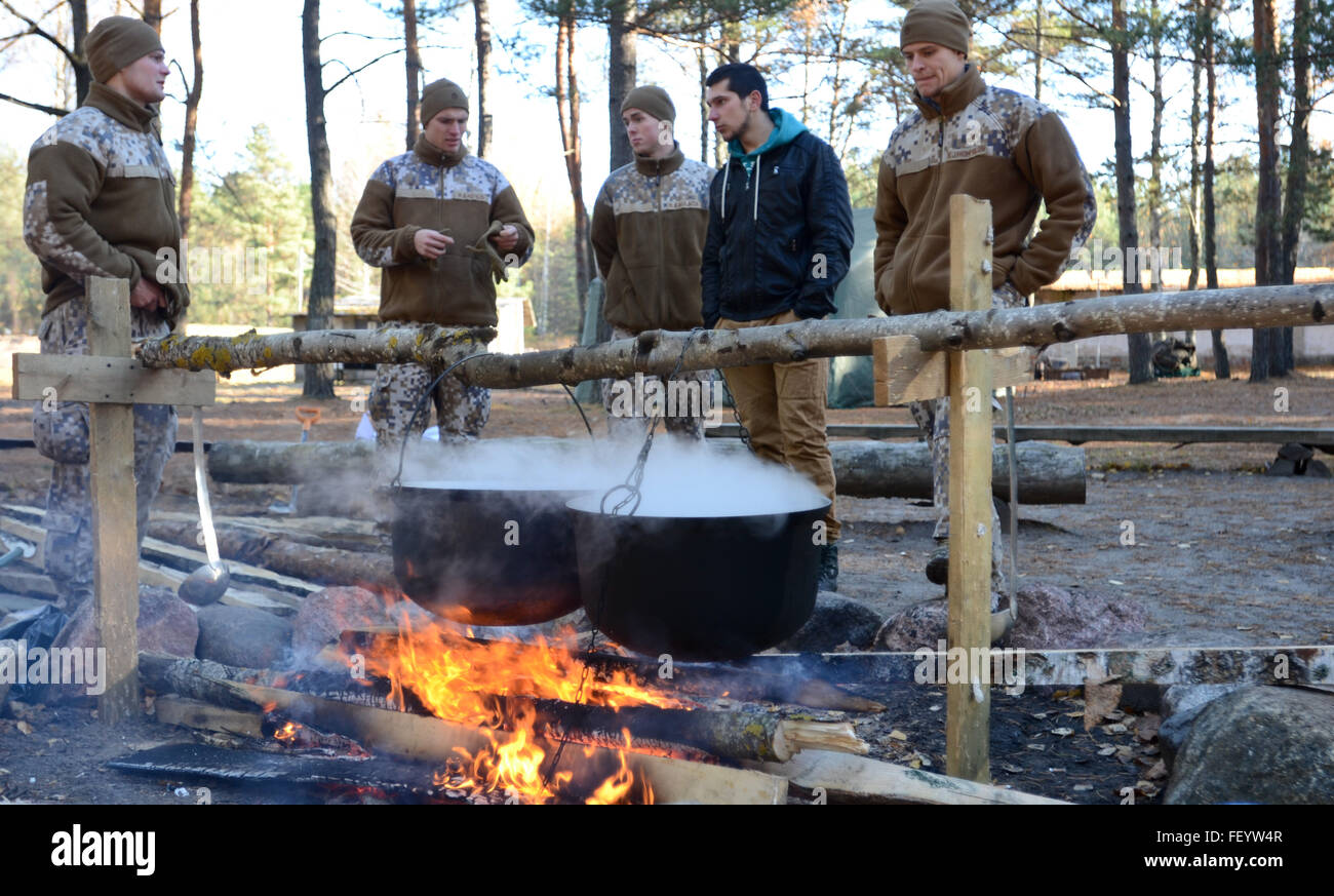Latvian cadets show civilian university students from Riga how food is prepared and cooked in the outdoors environment during the Cadet Path competition at a Latvian post in Adazi, Oct. 30-31, 2015. Latvian Cadets, civilian university students and United States Army soldiers participated in the 2nd Annual Cadet Path competition. The event featured civilian university students being taught basic military skills that were later tested during the competition by the Latvian cadets and U.S. Army soldiers. Stock Photo