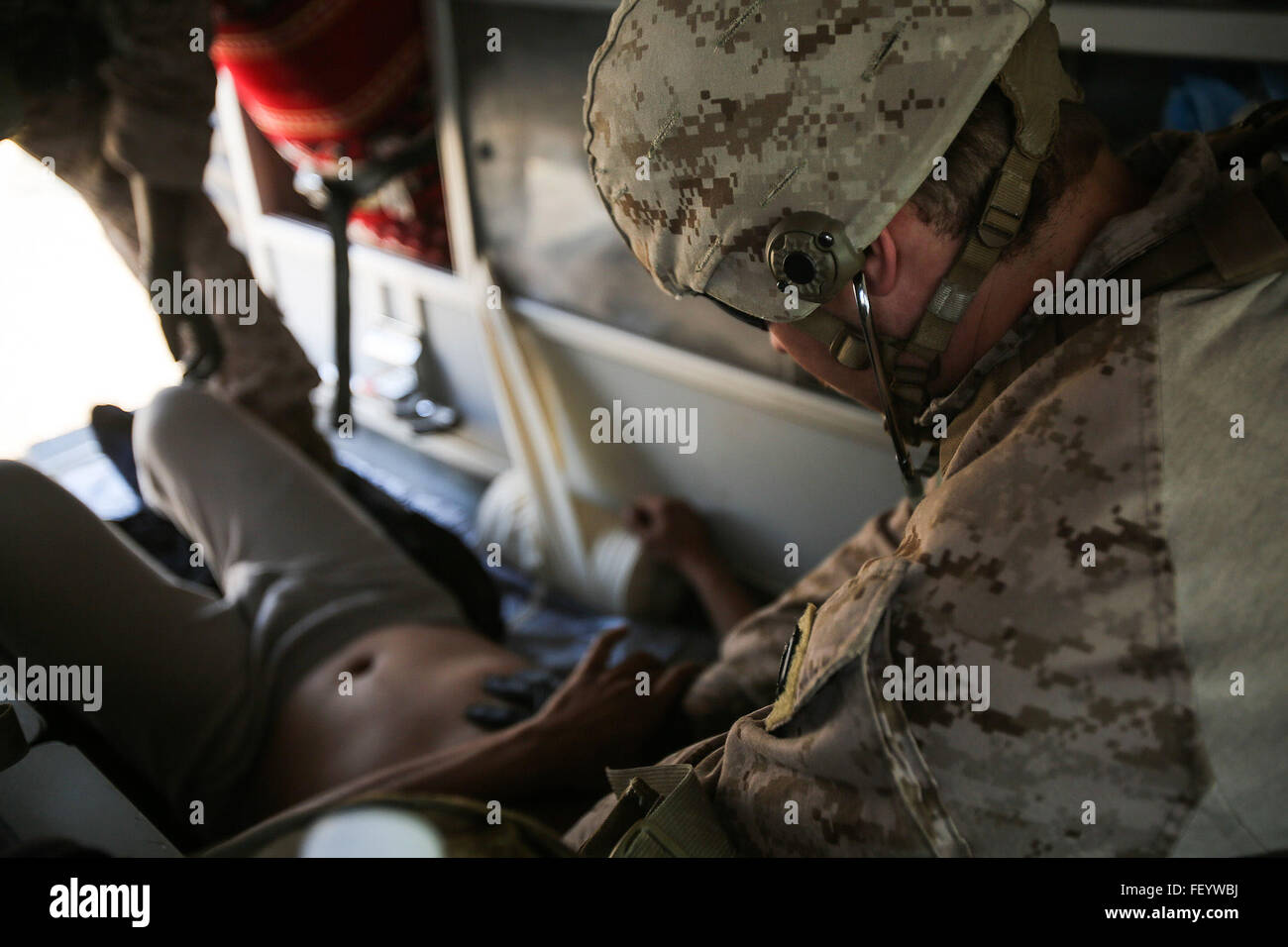 U.S. Navy Petty Officer 3rd Class Bryan Rileysilva, a hospitalman with Company B, 1st Battalion, 7th Marine Regiment, Special Purpose Marine Air Ground Task Force – Crisis Response – Central Command, treats an Iraqi soldier for combat-related injuries, Iraq, Nov. 28, 2015. Wounded Iraqi soldiers are occasionally transported from battlefields in Ramadi and Fallujah, Iraq, to Al Taqaddum to receive medical treatment from U.S. personnel. U.S. Navy corpsmen with “Bravo” Company, 1st Bn., 7th Marines, are the first responders to attend to the casualties. U.S. Marines and Sailors with SPMAGTF-CR-CC Stock Photo
