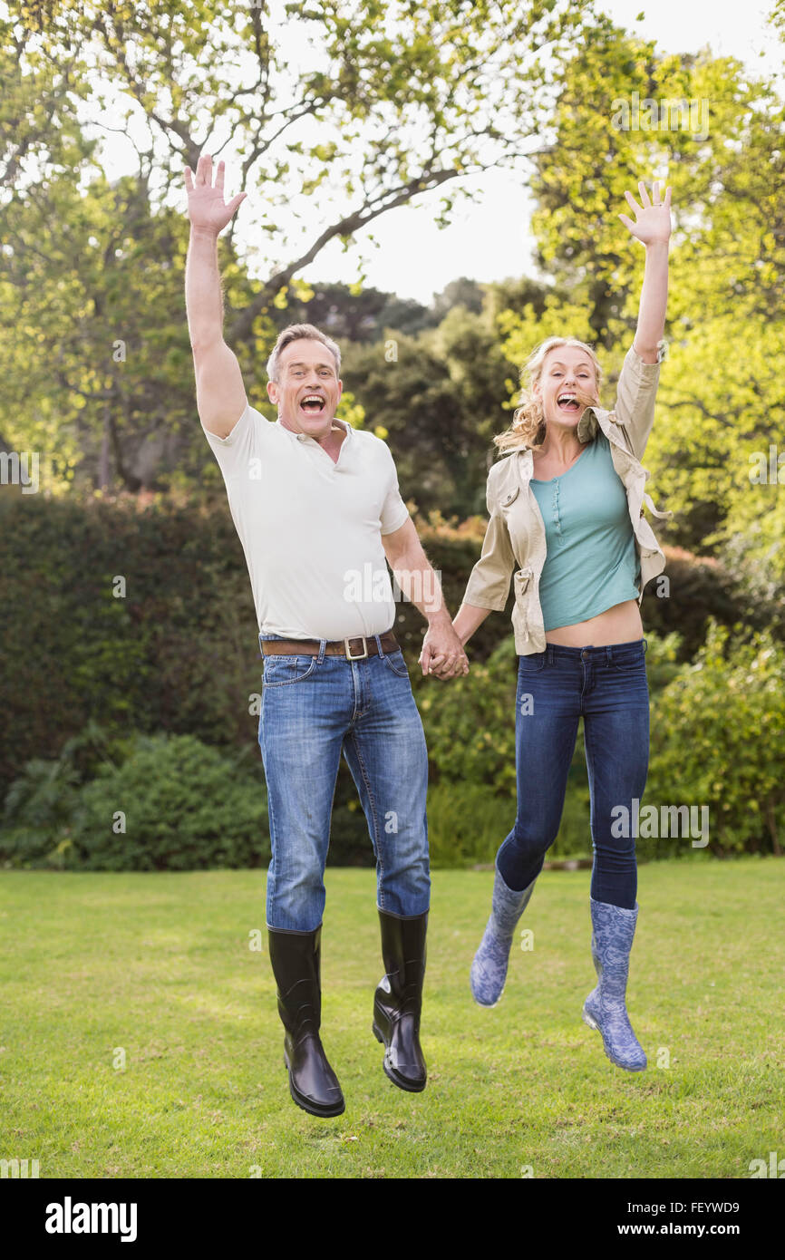 Cute couple jumping with arms in the air Stock Photo