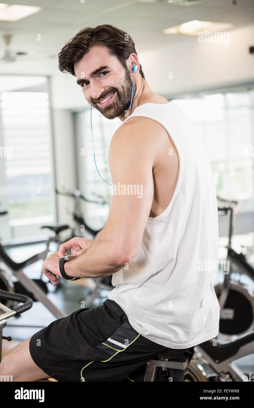 Smiling man on exercise bike using smartwatch Stock Photo - Alamy