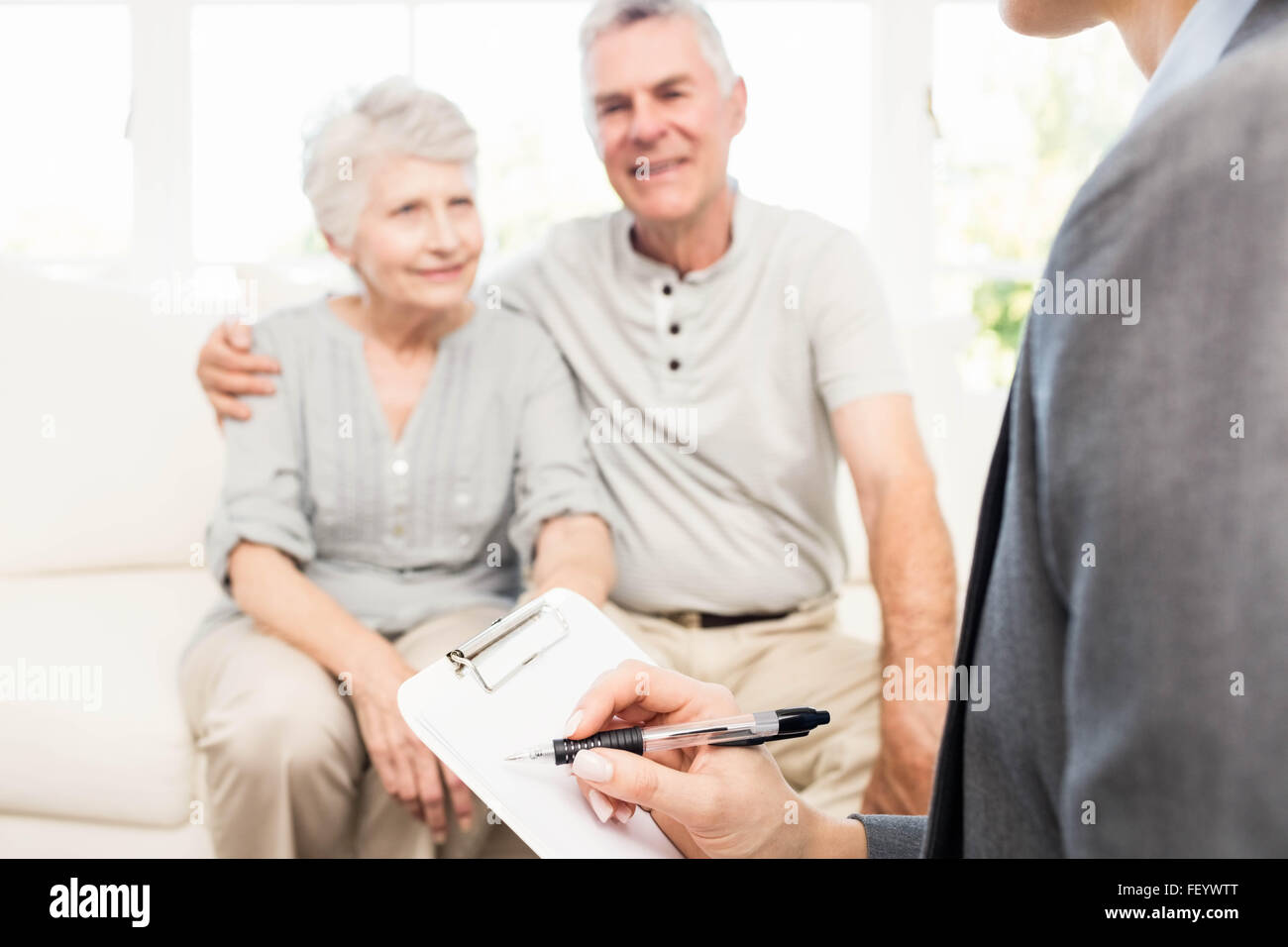 Businesswoman talking with senior couple and writing on clipboard Stock Photo