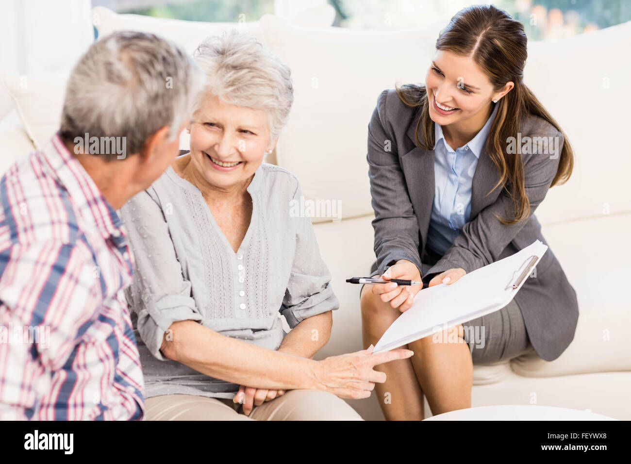 Smiling businesswoman showing documents to senior couple Stock Photo