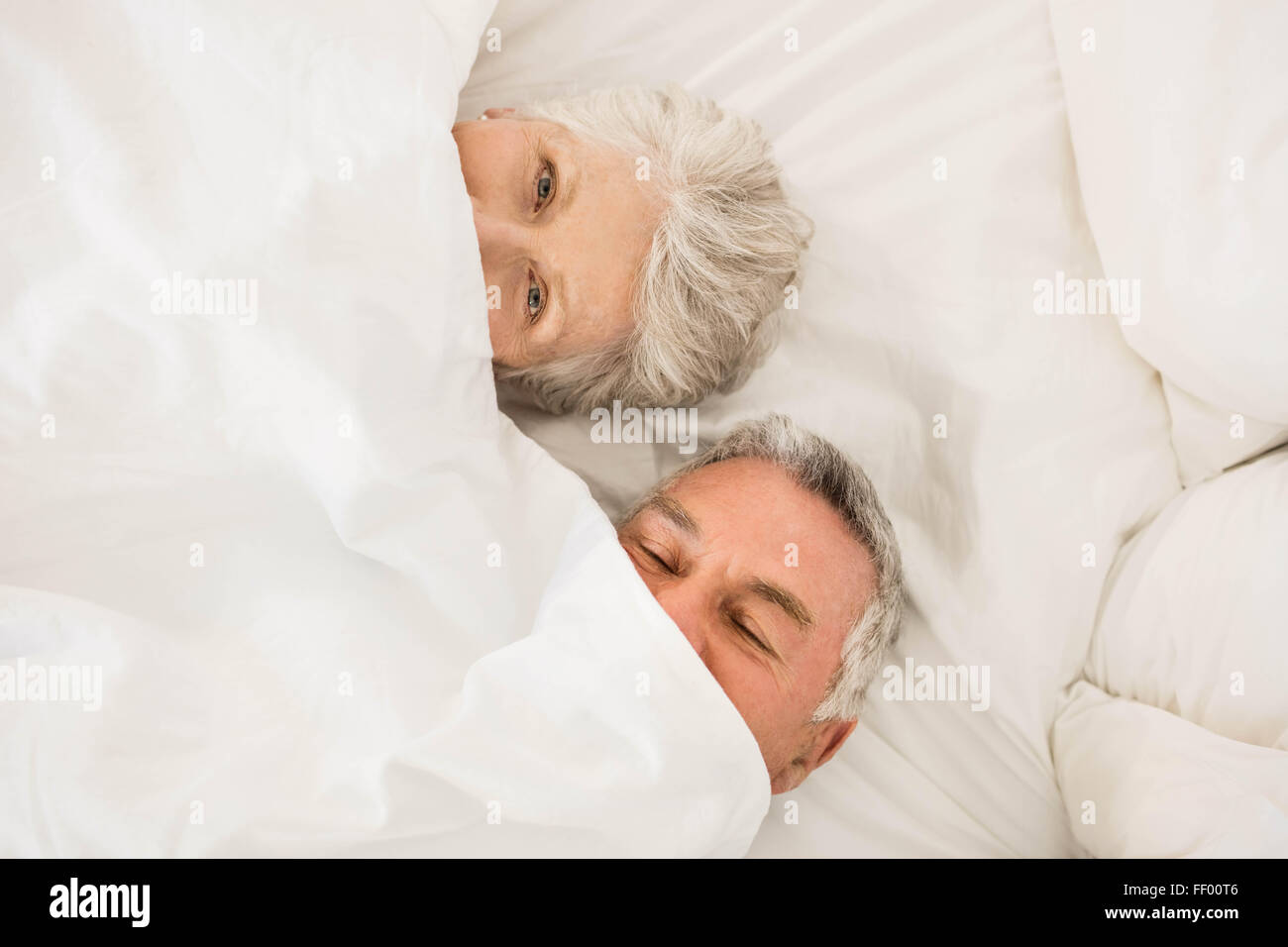Happy senior couple under duvet in bed Stock Photo