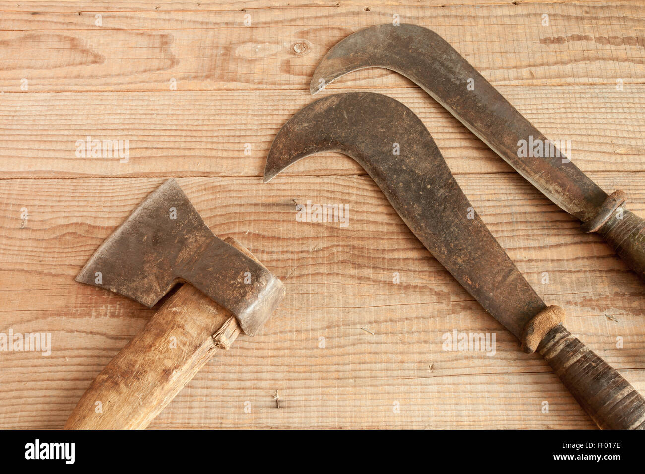 dated and used cleaver and two billhooks on wooden background Stock Photo