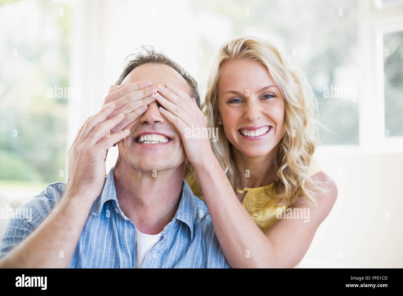 Happy wife covering husband eyes Stock Photo