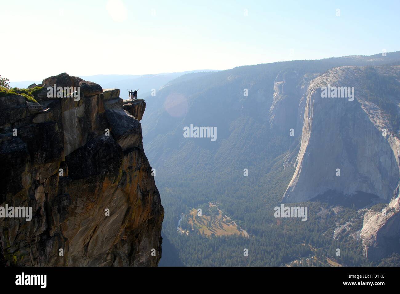 Four people raise their hands in celebration of making it to the top. Stock Photo