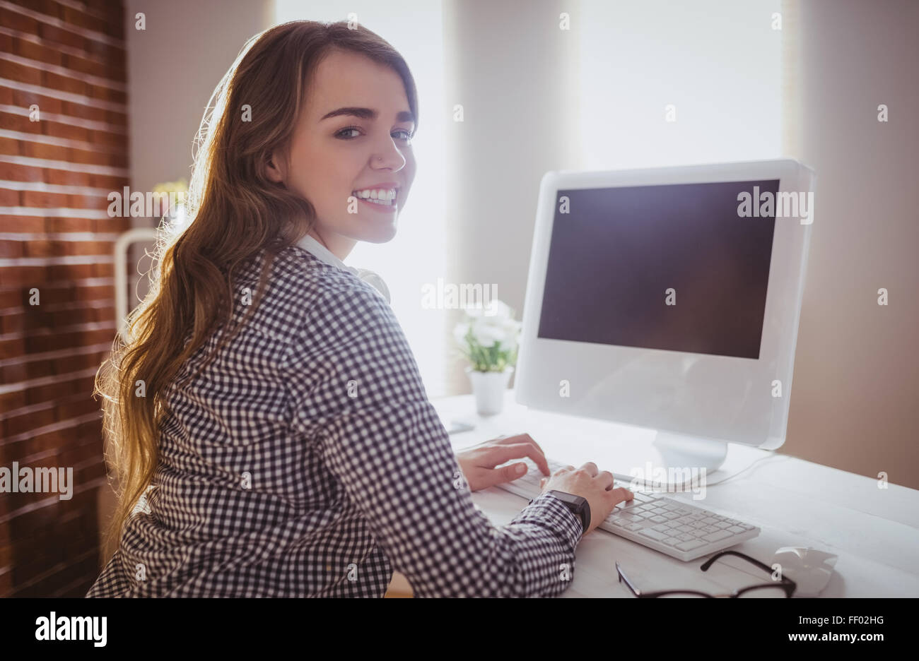 Smiling hipster businesswoman typing on computer Stock Photo