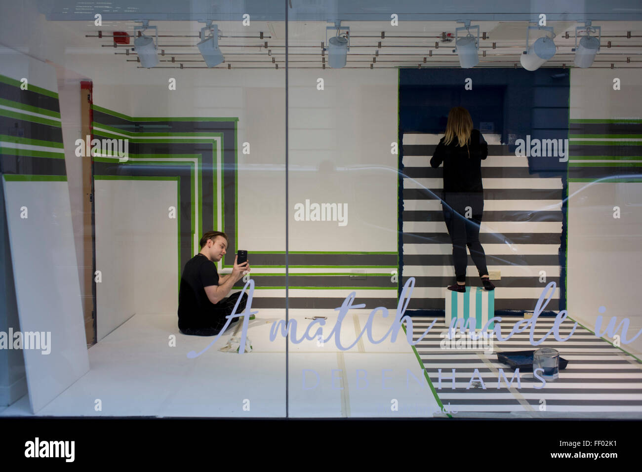 Window dressers prepare a new window design with a tripes theme in the oxford Street branch of retailer Debenhams. Stock Photo