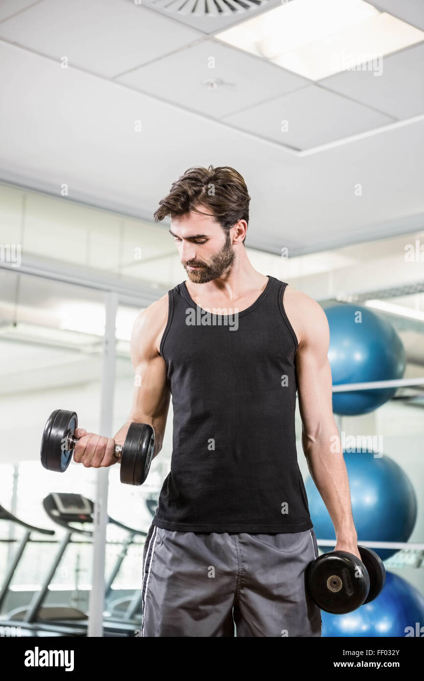 Concentrated man lifting dumbbells Stock Photo