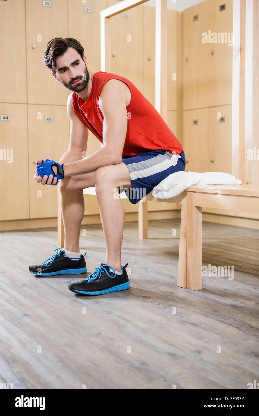 Unsmiling man sitting in locker room Stock Photo