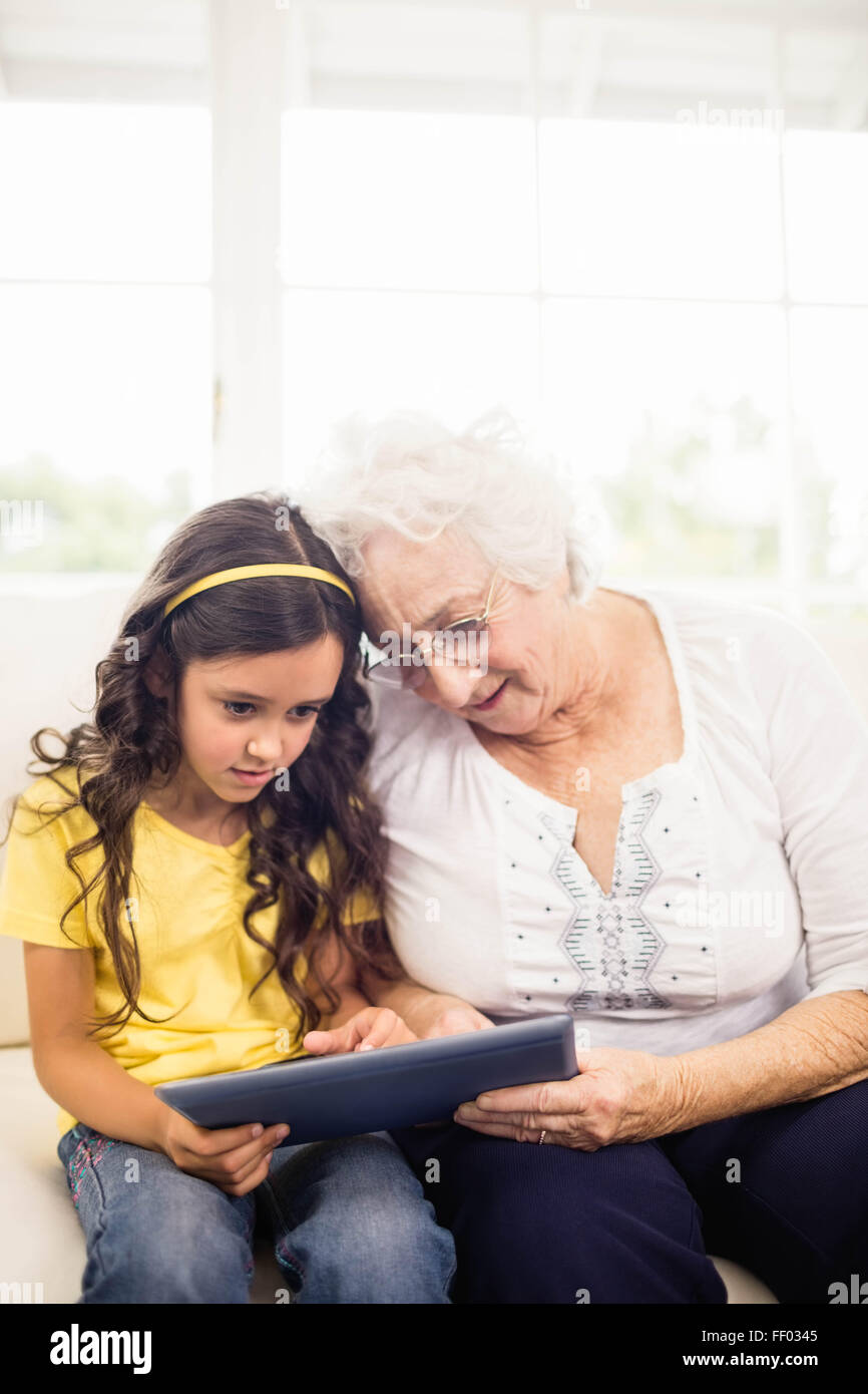 Concentrated granddaughter using tablet with grandmother Stock Photo