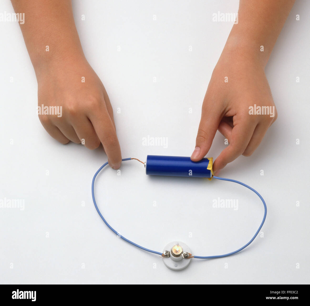Girl's hands connecting wire with battery, making simple electric curcuit, close-up Stock Photo