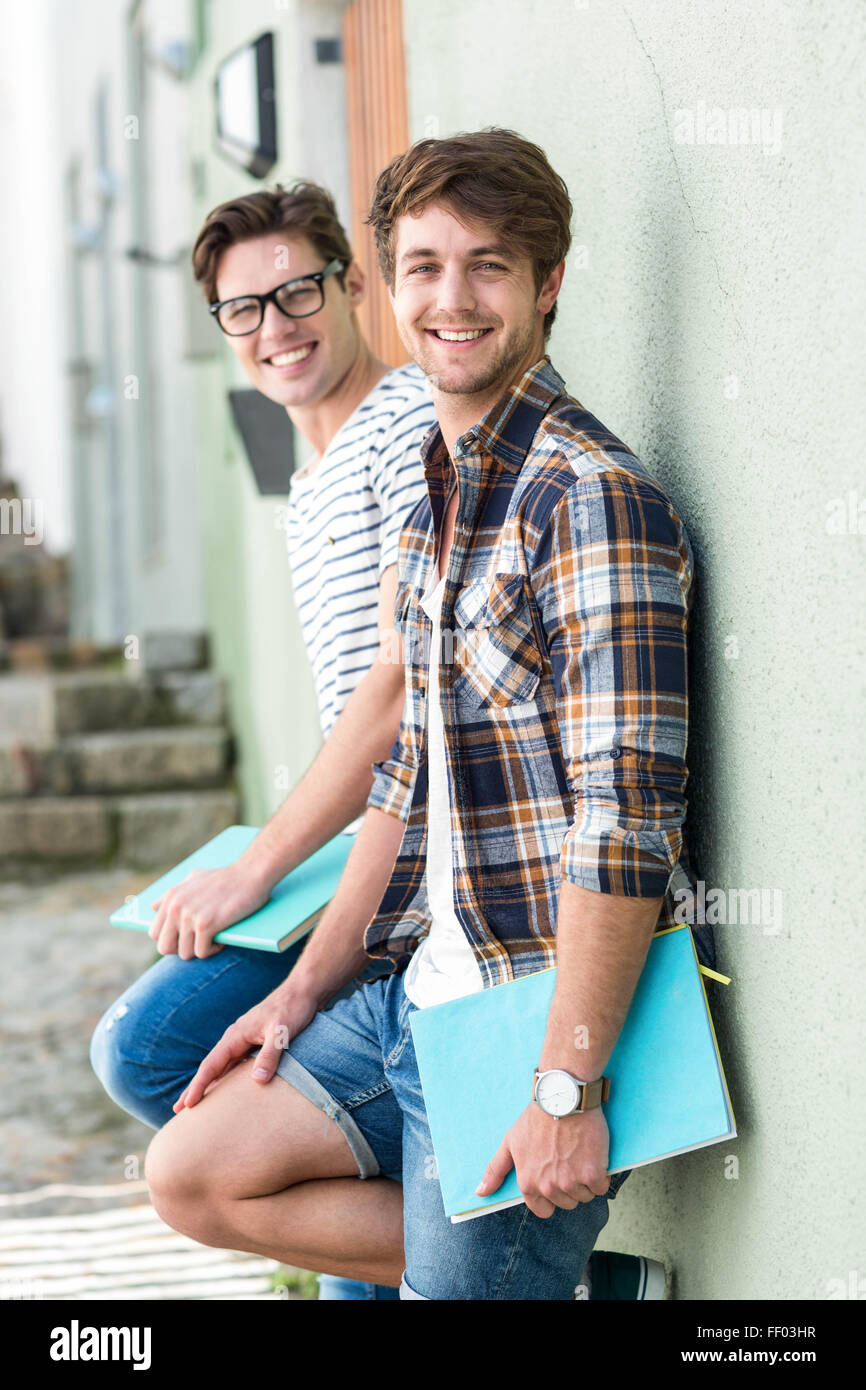 Hip men leaning against wall and holding notebooks Stock Photo