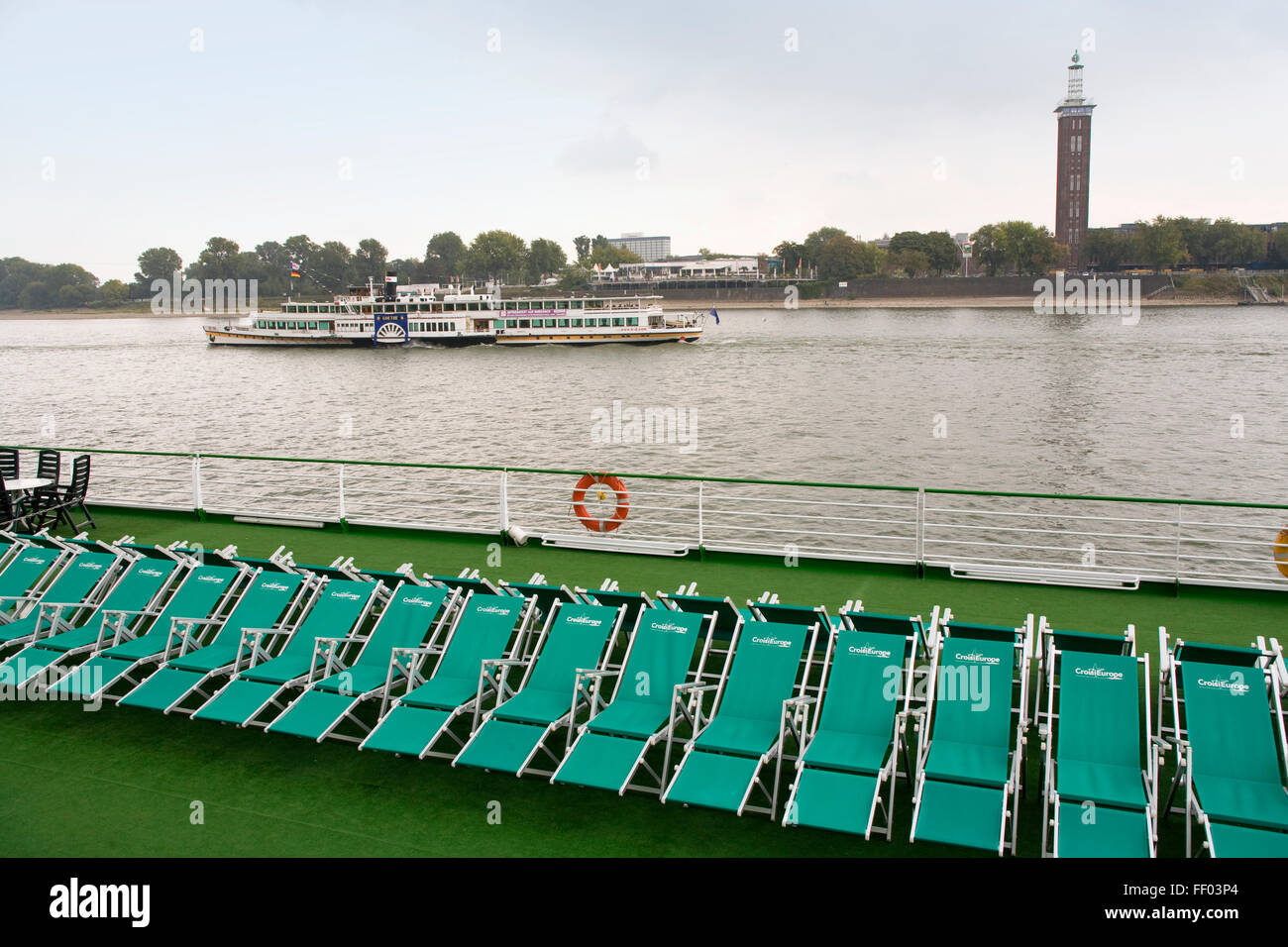 Europe, Germany, Cologne, sunloungers on the deck of a ship at the banks of the river Rhine, in thge  background the tower of th Stock Photo