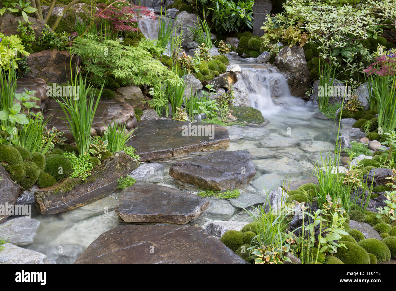 Edo no Niwa – Edo Garden – Japanese Zen garden with waterfall water feature stone stepping stones, moss covered stone UK Stock Photo