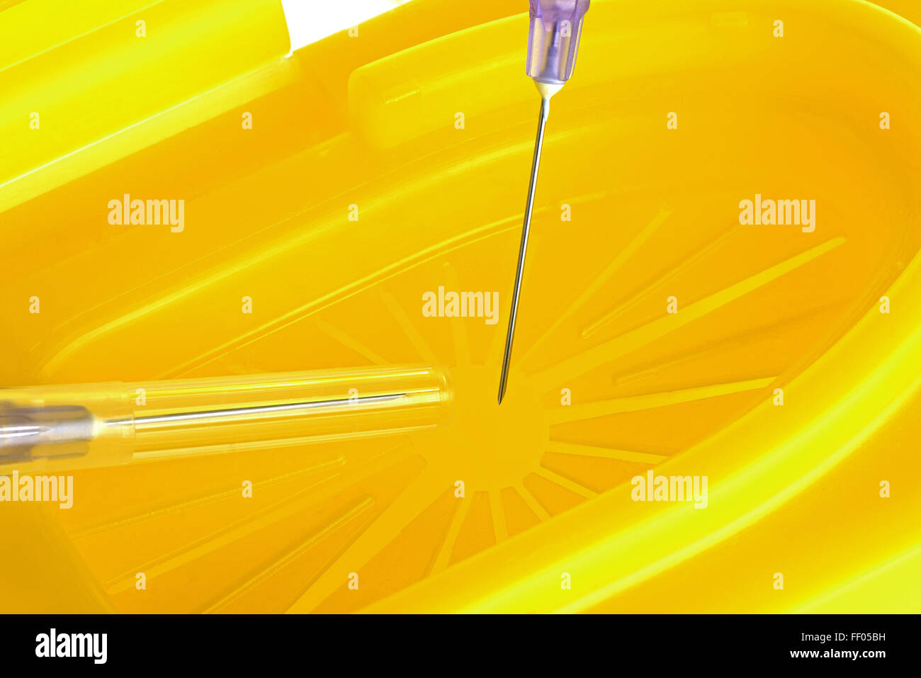 Hypodermic needles being put into a sharps disposal bin ready for safe