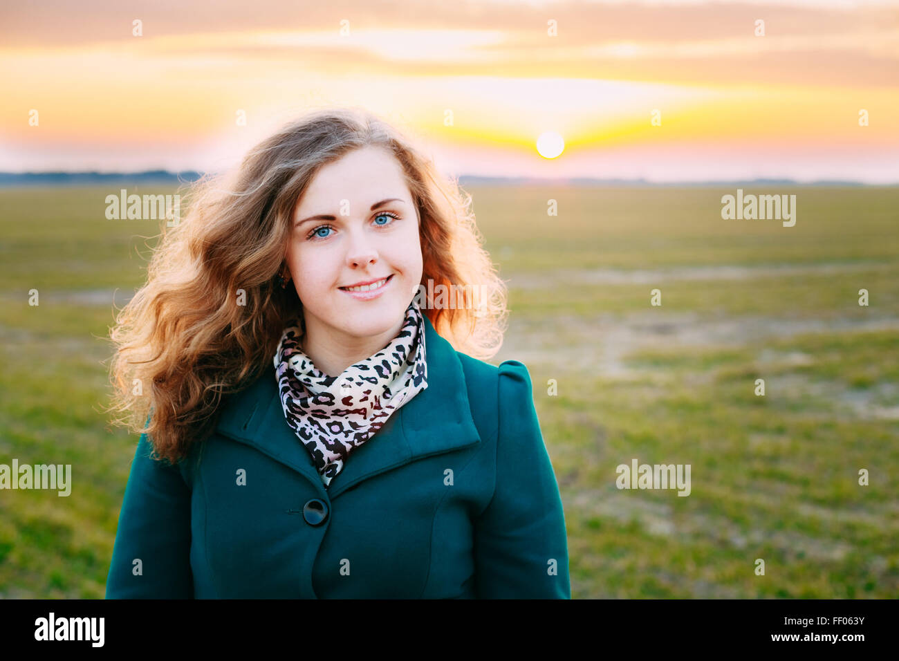 Portrait Of Beautiful Plus Size Young Woman In Blue Coat Posing In Field Meadow At Sunset Background. Spring, Outdoor Portrait Stock Photo
