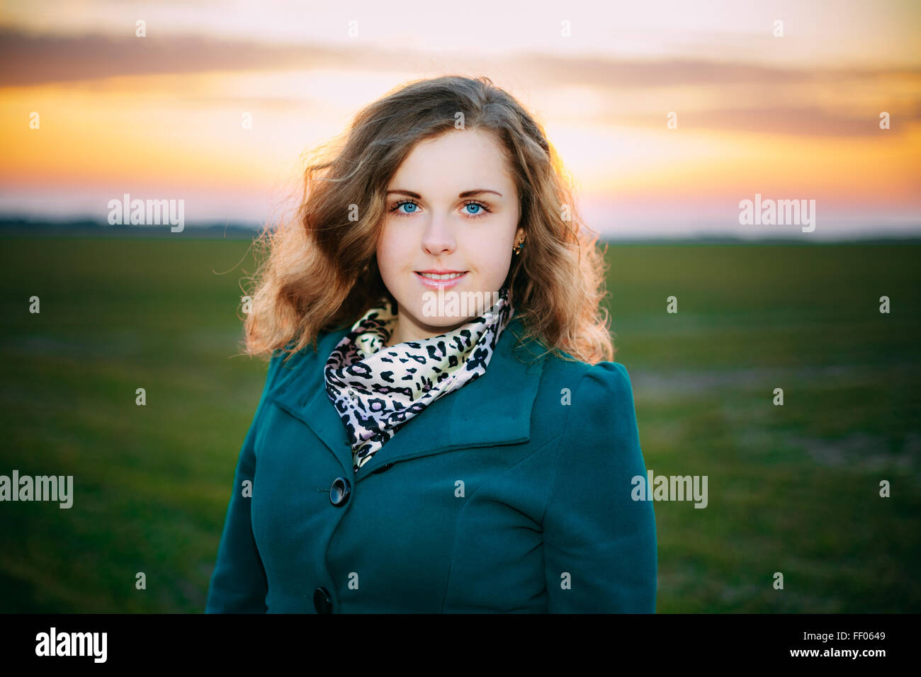 Portrait Of Beautiful Plus Size Young Woman In Blue Coat Posing In Field Meadow At Sunset Background. Spring, Outdoor Portrait Stock Photo