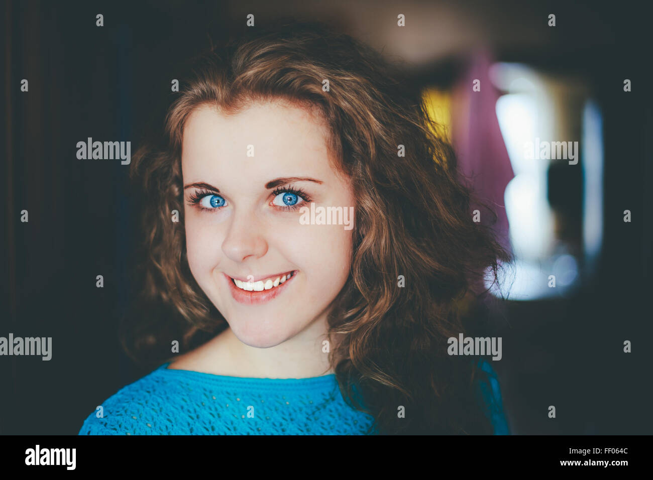 Portrait Of Beautiful Plus Size Young Woman In Blue Blouse Opening Door In Home, Looking Very Happy Stock Photo
