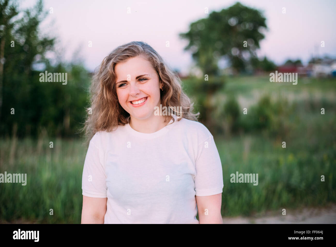 Portrait Of Beautiful Plus Size Young Woman In White Shirt Posing In Summer Field Meadow At Sunset Background. Spring, Outdoor P Stock Photo