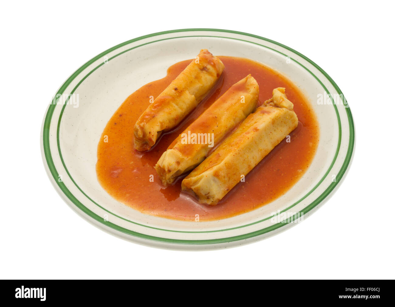 A serving of canned tamales in chili sauce on a plate isolated on a white background. Stock Photo