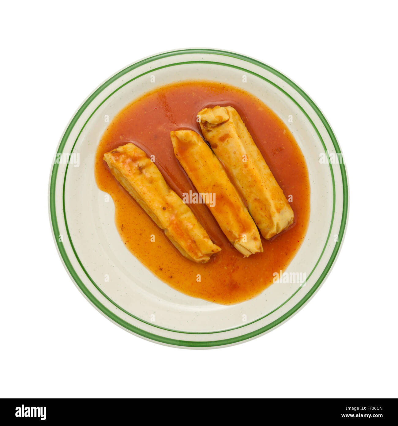 Top view of a serving of canned tamales in chili sauce on a plate isolated on a white background. Stock Photo