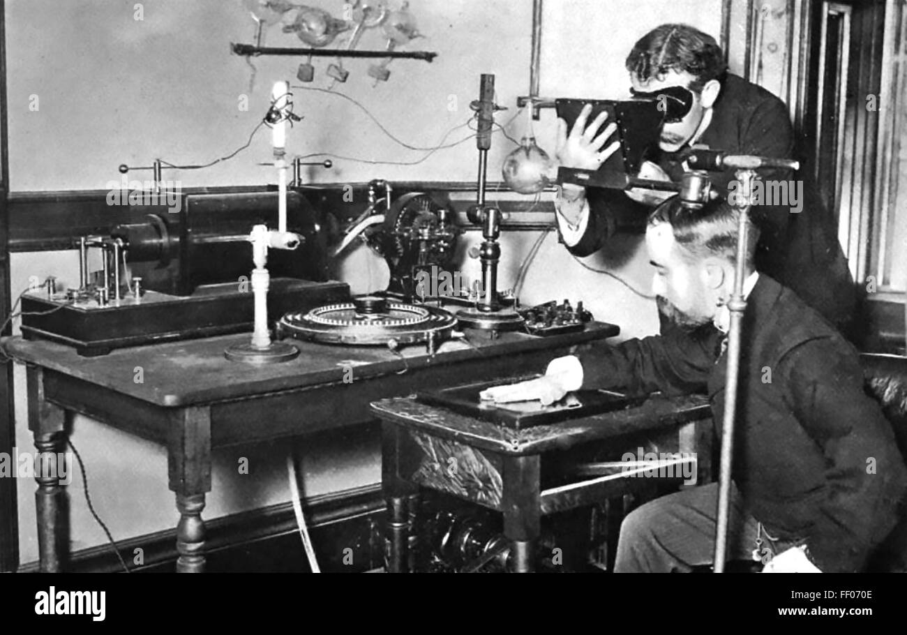 WILLIAM CROOKES (1832-1919) English chemist. Experimenters taking an x-ray photo with an early version of his Crookes Vacuum Tube about 1895. Stock Photo