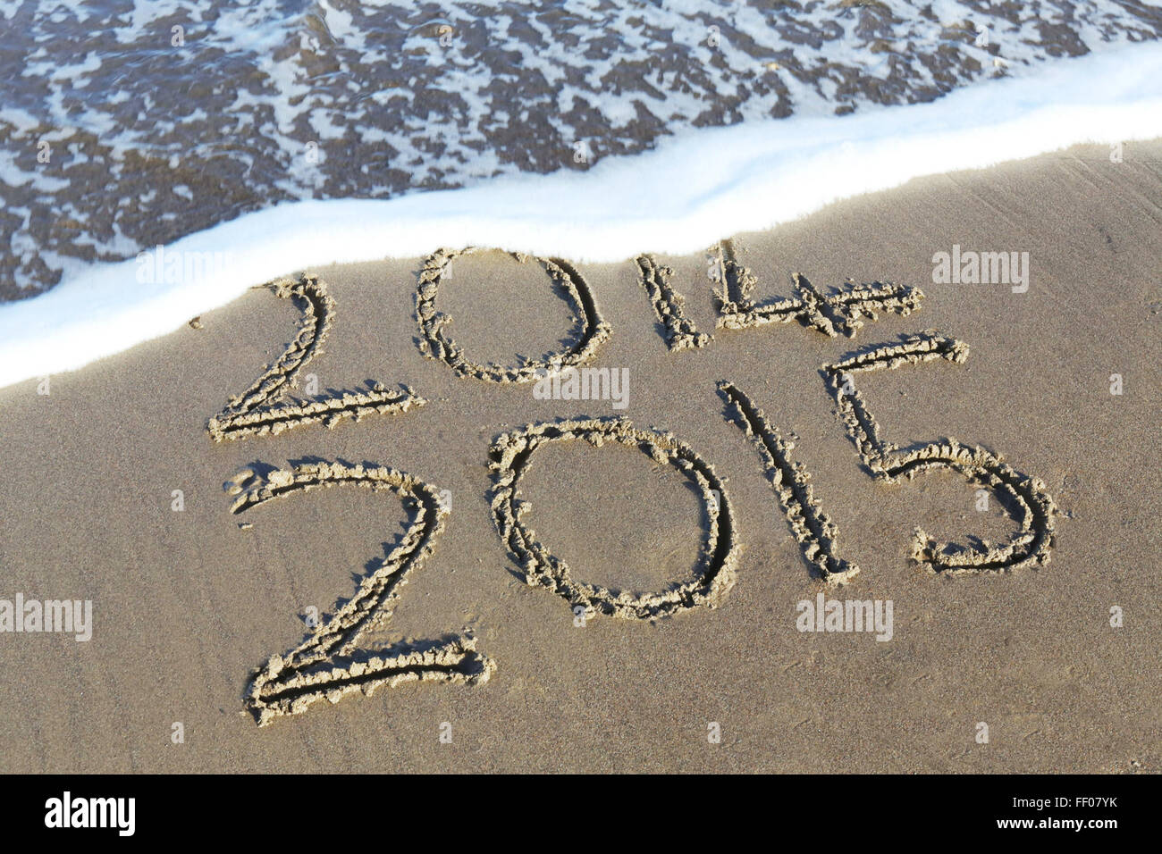 The numbers '2014' and '2015' written in the sand on a beach ...