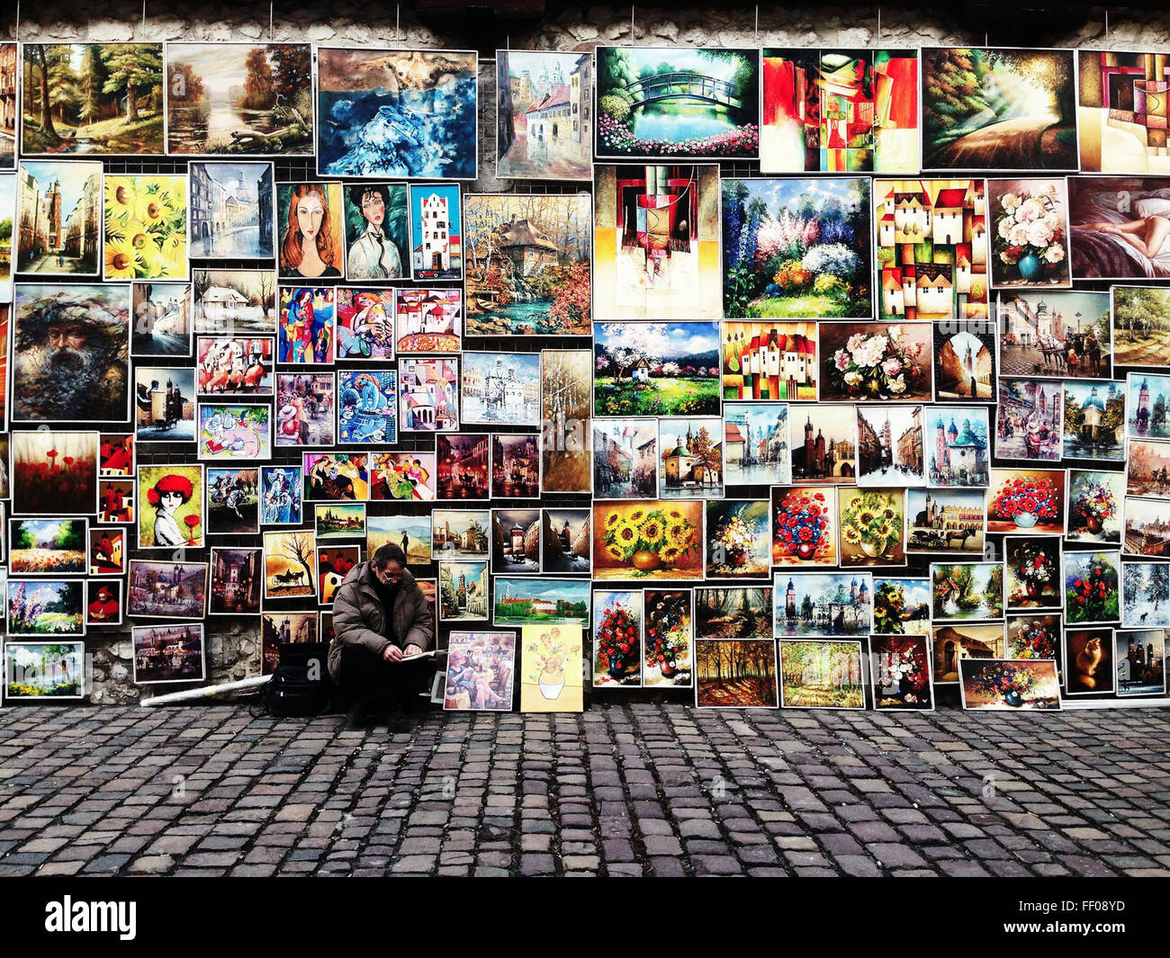 An art vendor displays a variety of colorful paintings and ...