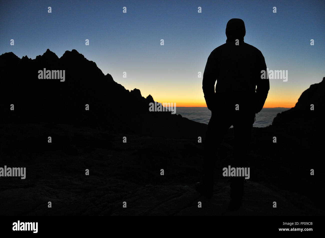 Silhouette of Person Standing on Landscape by Ocean Silhouette of Person Standing on Landscape by Ocean Stock Photo