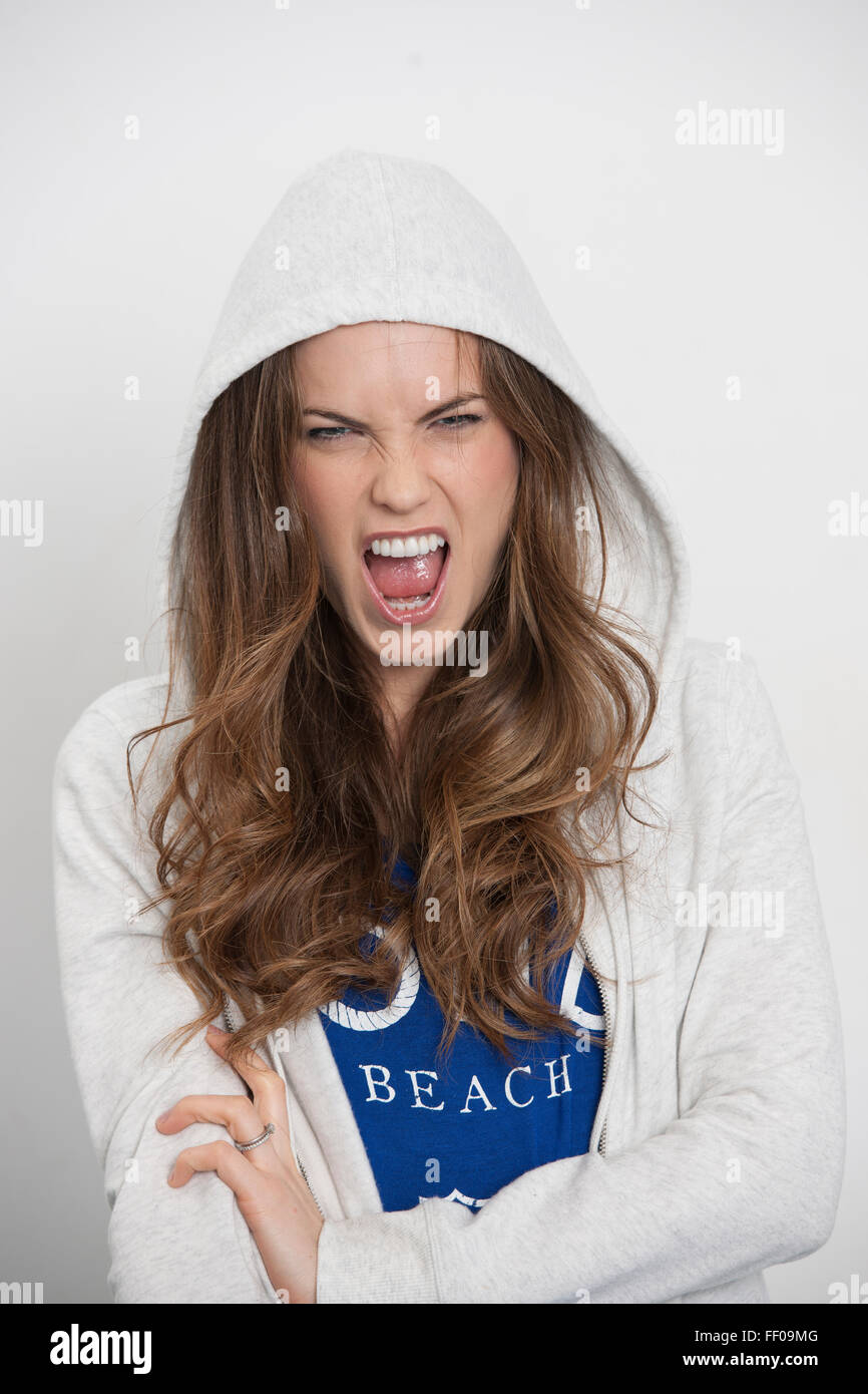 woman wearing a hoodie shouting, aggressive expression Stock Photo