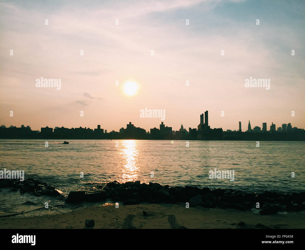 A vibrant sun rising or setting over a coastal city, casting a warm ...