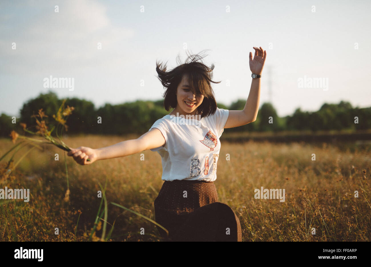 Female Holding Flowers Dancing in Field Stock Photo