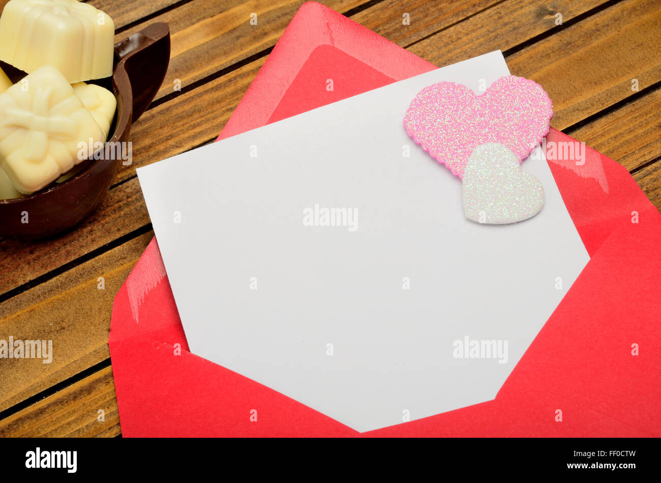 Red envelope with empty paper and chocolate gift on table Stock Photo