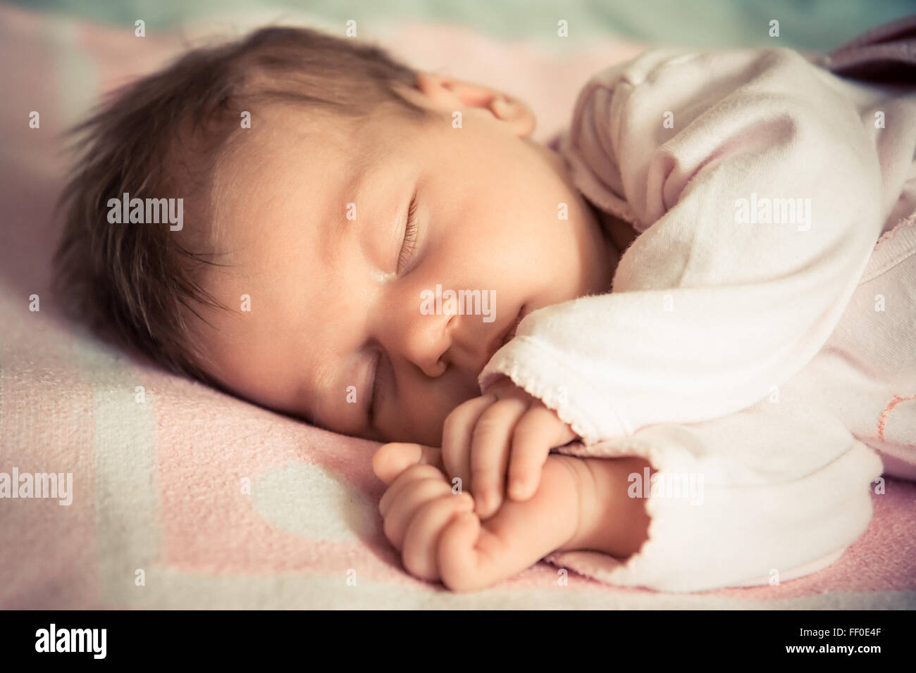 Newborn baby girl sleeping on soft blanket with natural light Stock